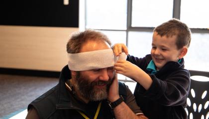 Child practices bandaging an adult