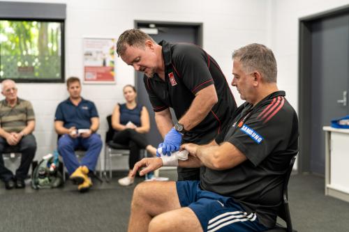 St John Trainer demonstrating bandaging someone in a first aid class