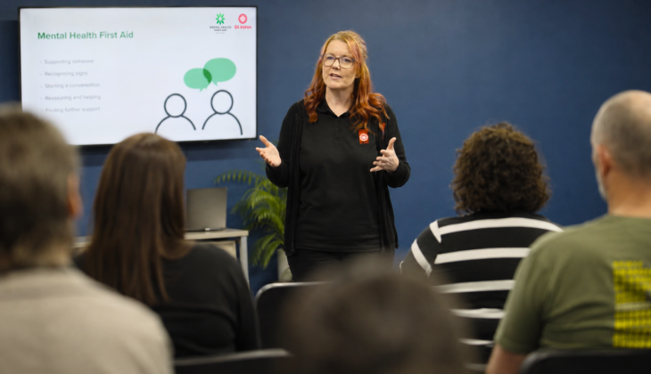 A mental health first aid classroom with a trainer speaking to a small group of people
