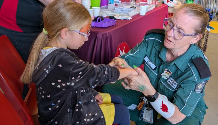Young girl and St John volunteer making fake wounds