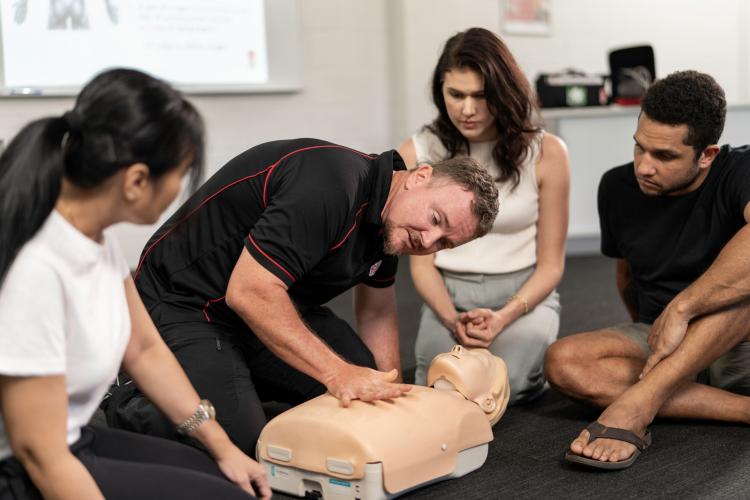 Photo of St John trainer demonstrating CPR to small group of students